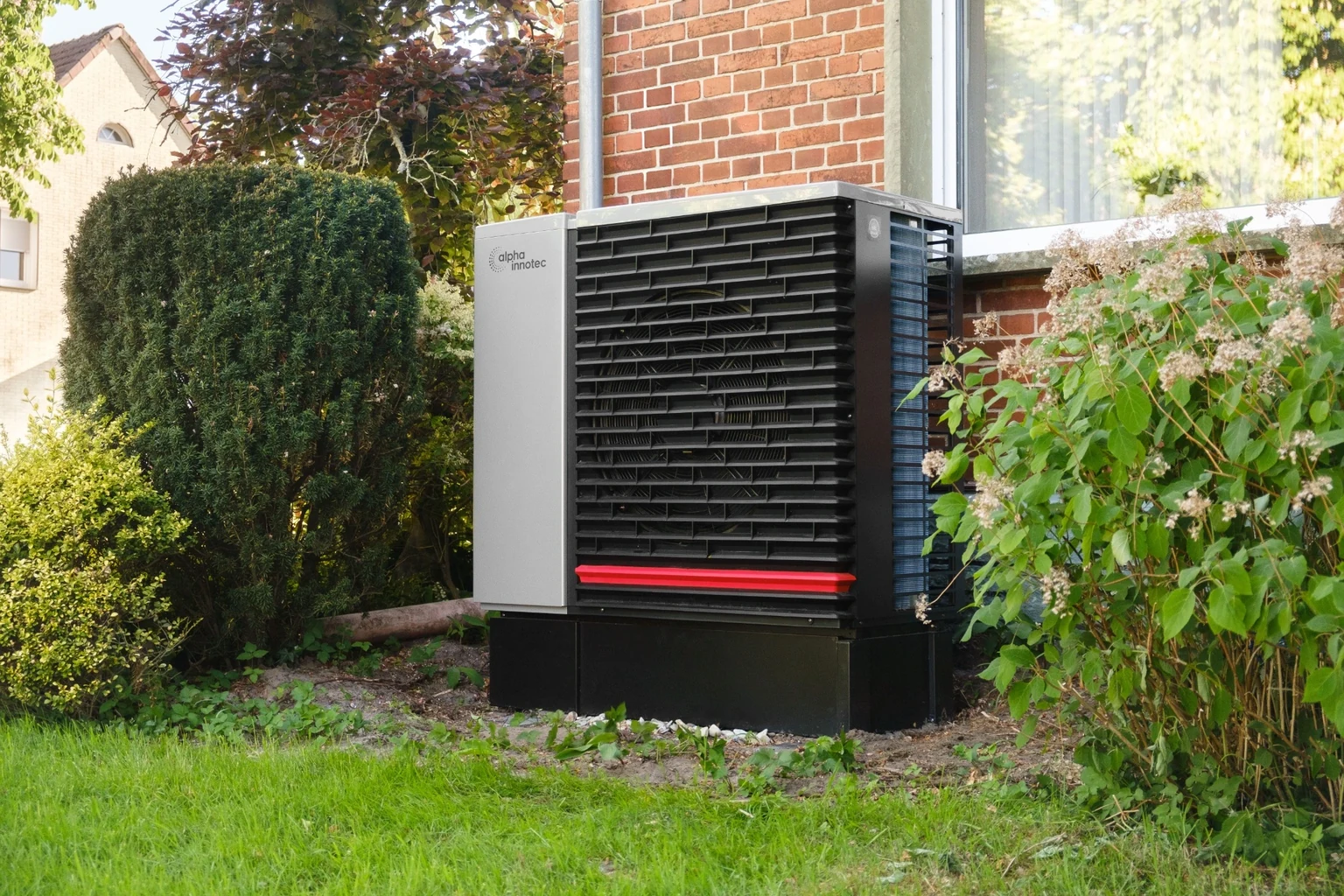 Pompe à chaleur extérieure Alpha Innotec devant un mur en briques